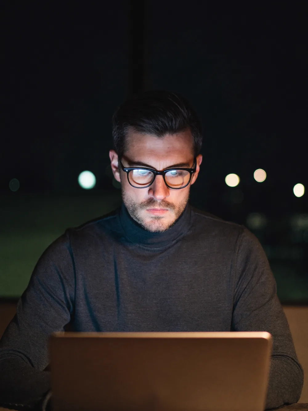 Security consultant working late, lit by a laptop screen