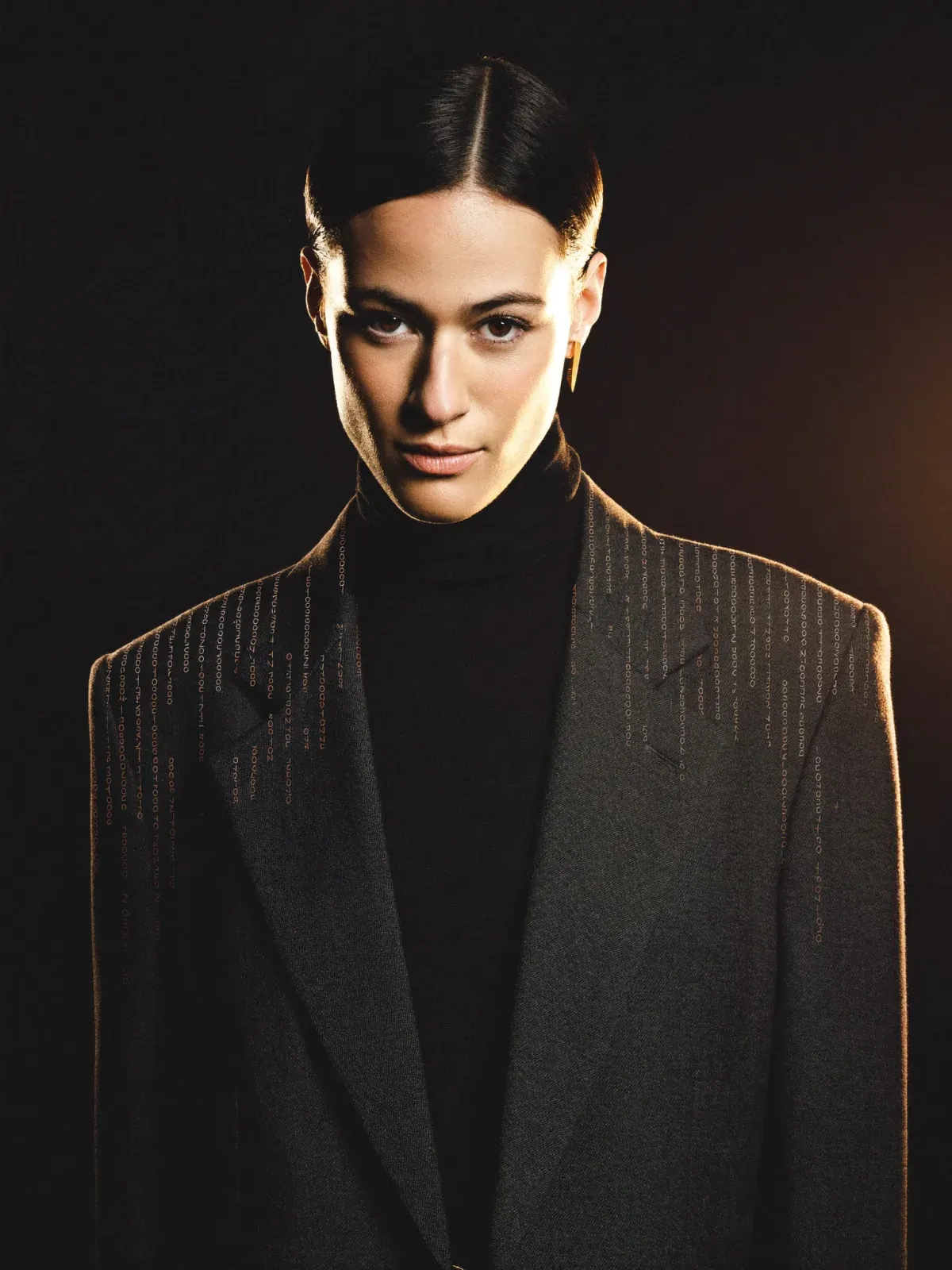 Portrait of a woman in a charcoal blazer, lit with warm light